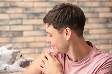 Doctor vaccinating man against flu in clinic