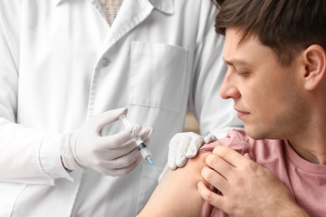Doctor vaccinating man against flu in clinic