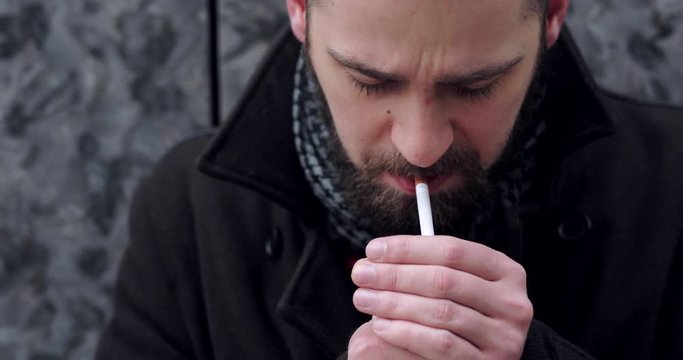 Bearded man walking on the city street and smoke cigarette 