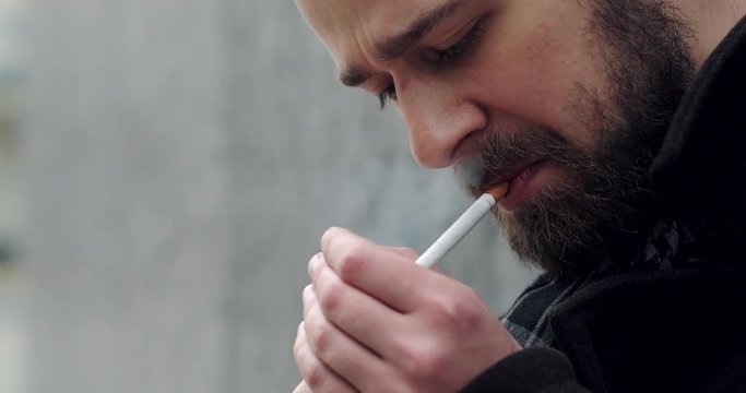 Bearded man walking on the city street and smoke cigarette 