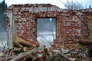 The remains of the old destroyed brick building are a wall with a window. In the window you can see the river and the fog