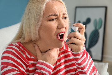 Mature woman with inhaler having asthma attack at home