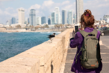 A female tourist takes a photo on the smartphone views from promenade