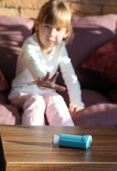 Obraz na płótnie Canvas Little girl taking inhaler from table