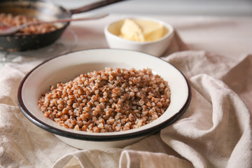 Bowl with tasty boiled buckwheat on table