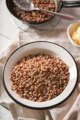 Bowl with tasty boiled buckwheat on table