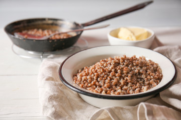 Bowl with tasty boiled buckwheat on table