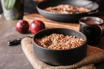 Bowl with tasty boiled buckwheat on grey table