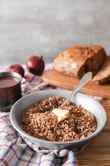 Bowl with tasty boiled buckwheat on wooden table