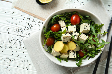 Tasty salad with tofu cheese in bowl on white table