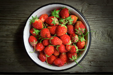 Fresh strawberry in a white plate on wooden table , top view