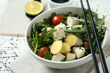 Tasty salad with tofu cheese in bowl on white table