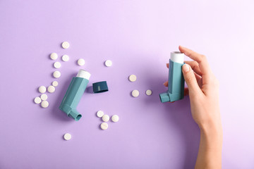 Female hand with inhaler and cure against asthma on color background - obrazy, fototapety, plakaty