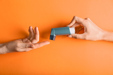 Female hands with inhaler against asthma on color background - obrazy, fototapety, plakaty