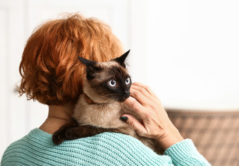 Mature woman with cute funny Thai cat at home