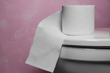 Roll of paper on toilet bowl cover in restroom