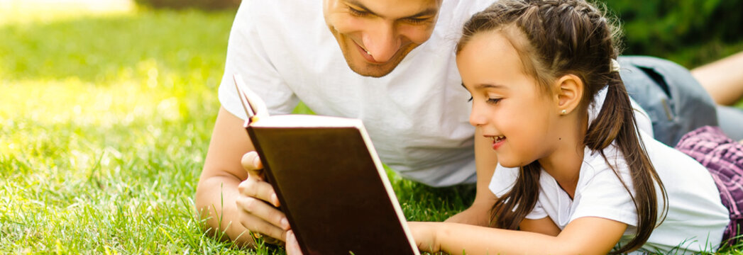 Happy Parent With Child Reading The Bible In Nature