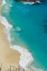 Vertiginous, swirling foamy water waves at the ocean photographed from above cliff.