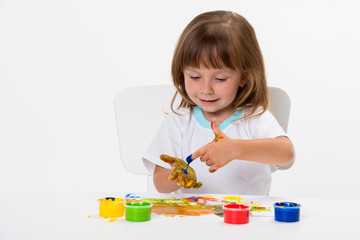 Close-up portrait of a cute cheerful happy smiling little girl draws her own hands with gouache or finger paints isolated on white background