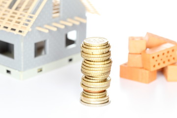 Finanzierungssymbol mit Rohbau und Geldmünzen