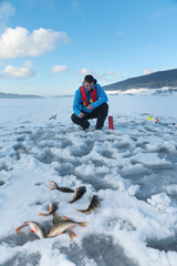 Fisherman catching fish on a frozen lake on the snow. Ice fishing. Selective focus