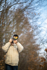 Senior man devoting time to his favorite hobby - photography - taking photos outdoor with his digital camera/DSLR and a big telephoto lens