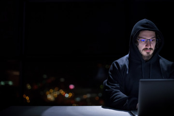 hacker using laptop computer while working in dark office