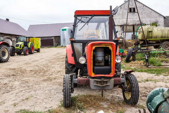 Old tractor for works in a fields ,where cultivated corn and grass for the cows . Front view of an agricultural machine. Equipment for a dairy farm.