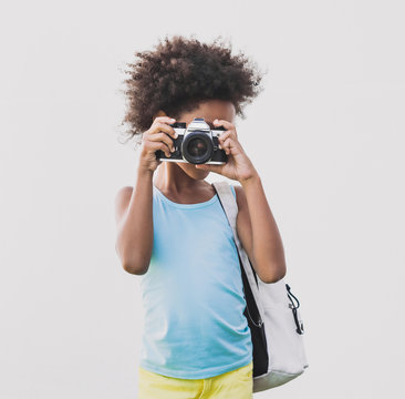 Happy smiling little girl taking pictures on a digital camera. Beautiful kid girl portrait.  Isolated on gray background. Summer fun, vacations concept