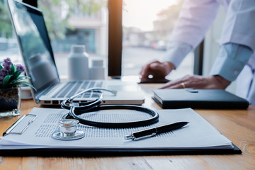 Patient listening intently to a male doctor explaining patient symptoms or asking a question as they discuss paperwork together in a consultation