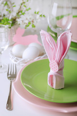 Happy easter. Decor and table setting of the Easter table is a vase with pink tulips and dishes of pink and green color.