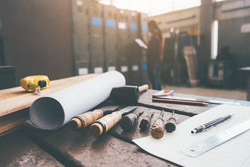 Equipment on wooden desk with man working in workshop background.