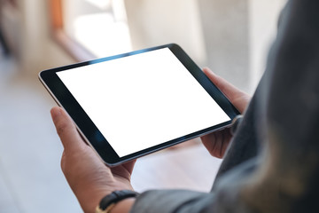 Mockup image of woman's hands holding black tablet pc with blank screen horizontally in cafe - obrazy, fototapety, plakaty