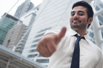 asian business man pointing thumb up gesture; portrait of Asian, north indian successful and confident businessman points his approving, yes, ok thumb up