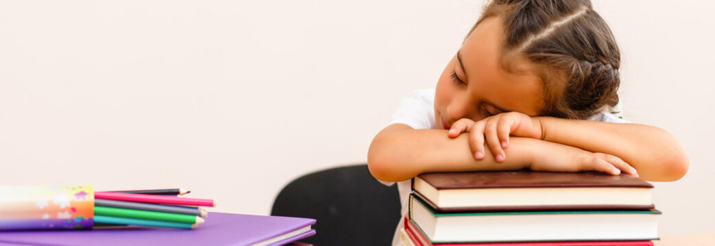 Portrait of fatigued schoolgirl sleeping on book