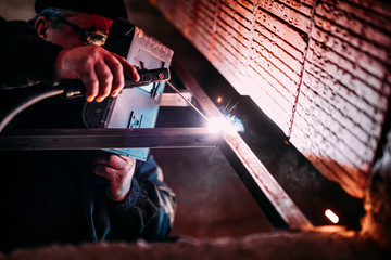 Industrial Worker laborer at the construction site, welding steel structure