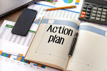 Business accessories, smartphone calculator, laptop, reports and diary with text Action plan