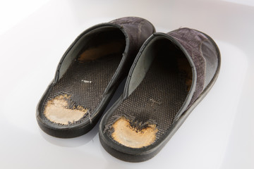 Old black slippers isolated on white background