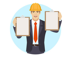 Businessman in construction helmet holding two clipboards