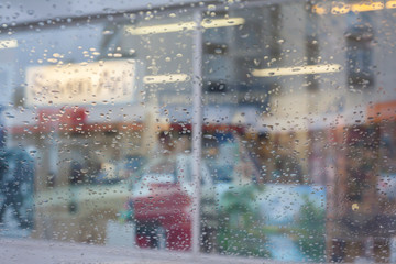 Rain drops on car glass, focus on raindrops. View to the street.
