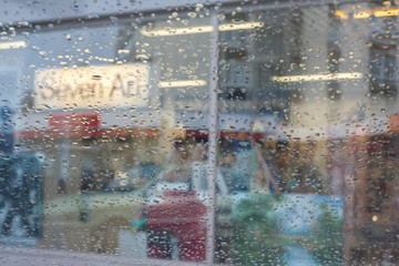 Rain drops on car glass, focus on raindrops. View to the street.