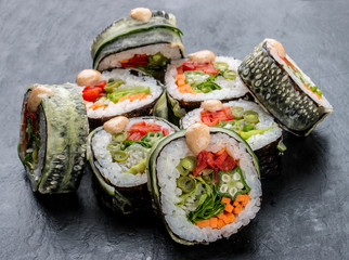 Sushi roll with vegetables on black background. Vegetarian dish.