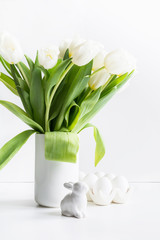 Easter. White tulips in vase, bunny, white eggs on white.