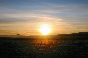 Spectacular golden sunrise on cleaned agricultural field with smooth hills on horizon in Khakassia, Russia