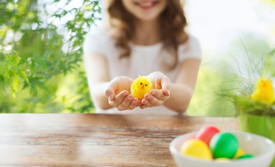 easter, holiday and child concept - close up of girl holding yellow toy chicken over green natural background