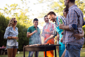 Young and happy people grilling outdoors in nature