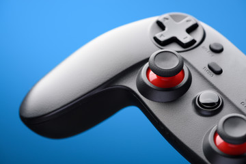 Video game controller. Game pad player joystick closeup on blue background.
