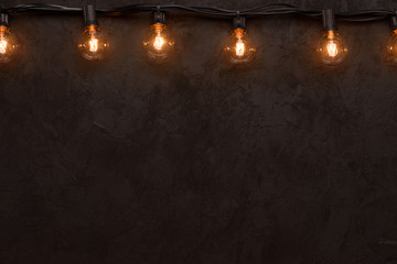 Light bulb string light on dark background top border with copy-space
