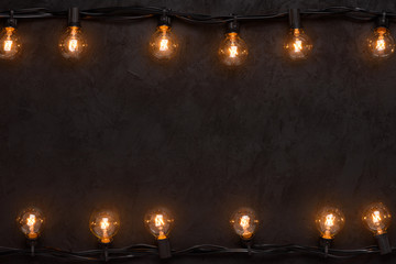 Light bulbs retro garland on dark black wall background