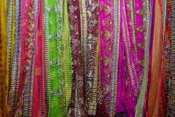 Rolls of fabric and textiles, silk for sale stacked on shelves in shop, View of cloth rolls of different colors and patterns on shelves in fabric store, Colorful traditional indian, turkey costumes